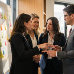 Deux femmes et un homme en réunion dans un bureau moderne et créatif, discutant devant une grande surface couverte de post-it colorés.
